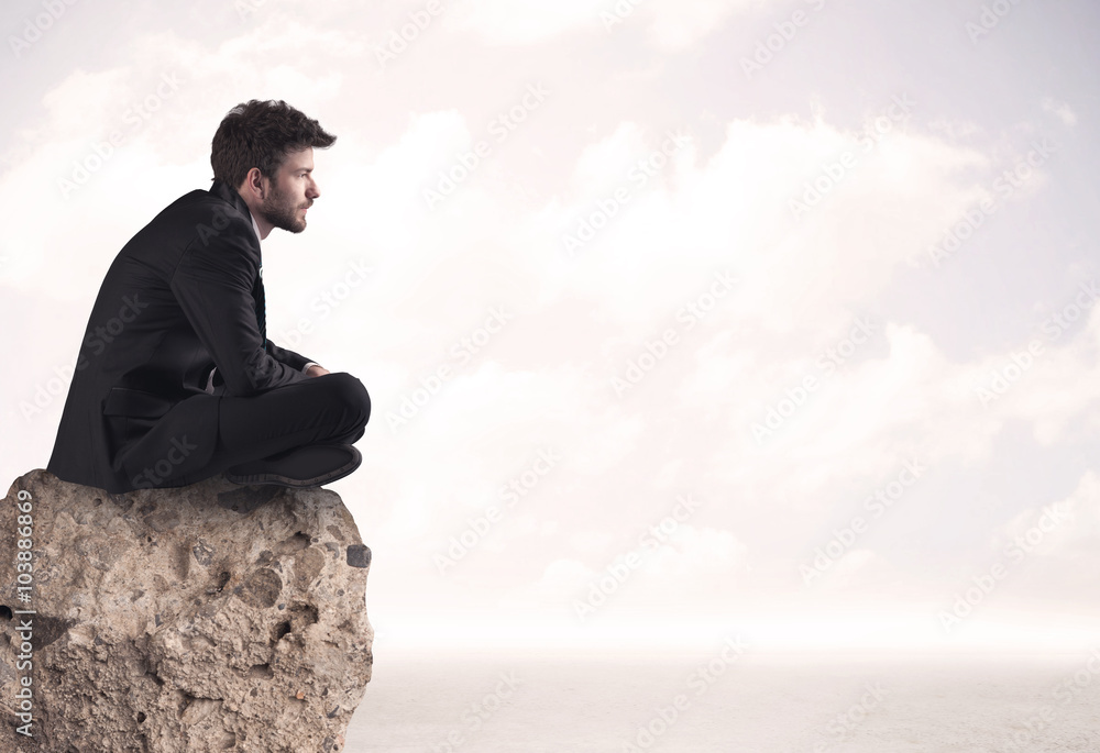 Business man sitting on stone edge