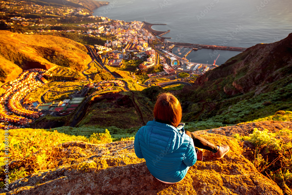 Young female traveler in blue jacket enjoying landscape view on Santa Cruz city on La Palma island in the morning