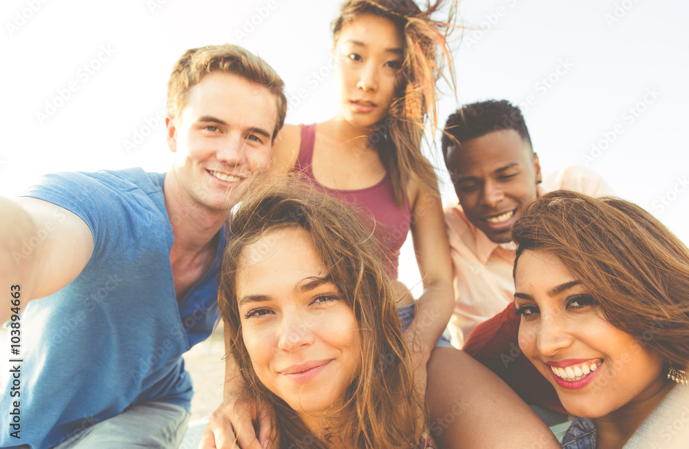 Mixed race group of friends walking in Santa monica beach and taking selfie Mixed race group of friends walking in Santa monica beach and taking selfie