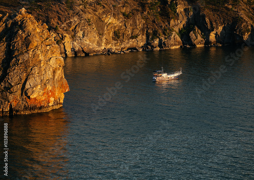 Boat near rocks at sunset on the lake Baikal