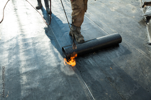 Fotótapéta Installation of roll roofing waterproofing propane blowtorch during construction