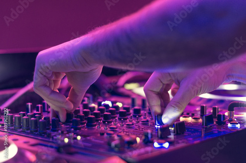 Dj mixes the track in the nightclub at party - music and technology concept