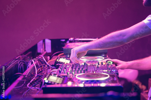 Dj mixes the track in the nightclub at party - music and technology concept photo