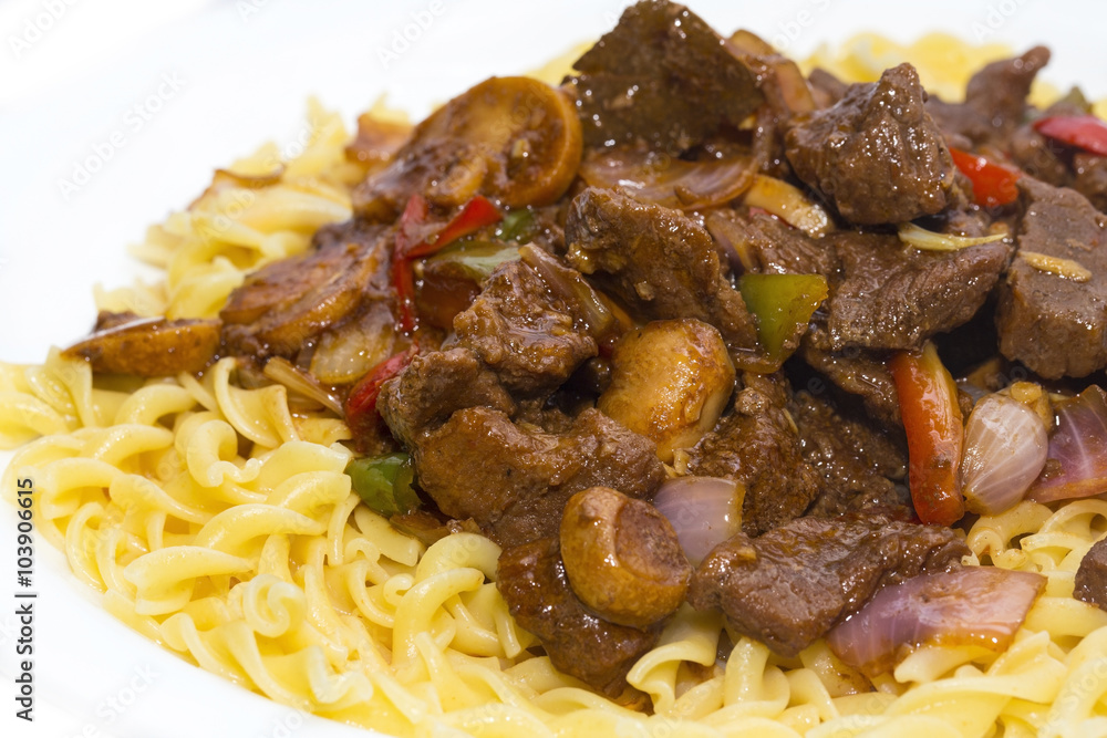 pasta with pork and mushrooms on a white plate in a restaurant pasta with pork and mushrooms on a white plate in a restaurant