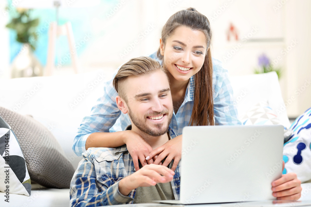 Happy couple sitting at the table and working with a laptop Happy couple sitting at the table and working with a laptop