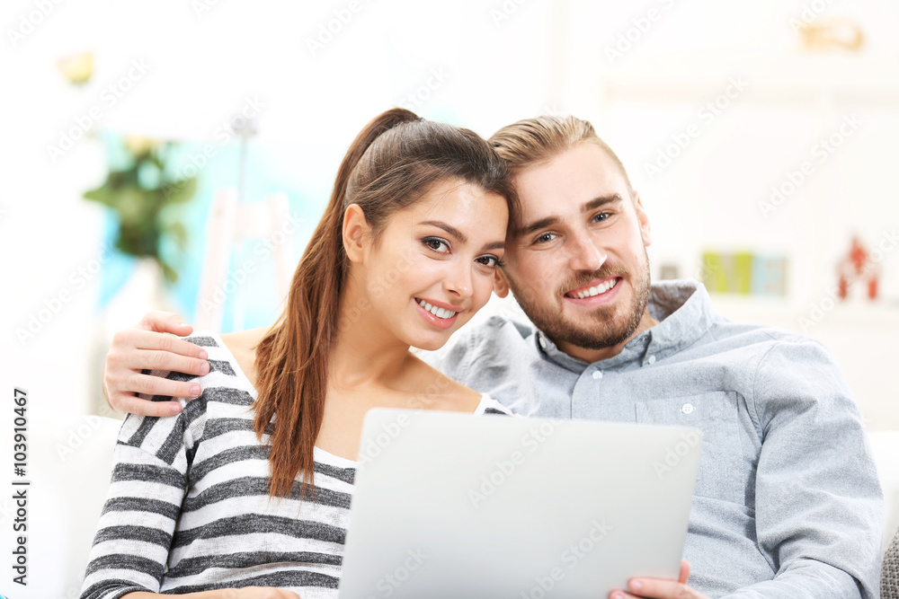 Happy couple sitting on sofa and working on a laptop Happy couple sitting on sofa and working on a laptop