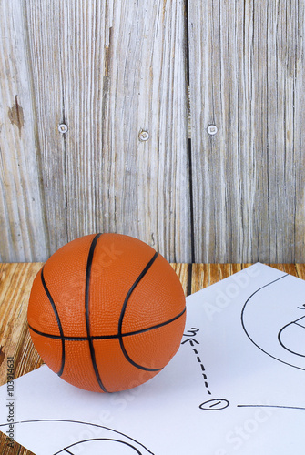 An orange basketball and a play diagram good for March madness, championship or basketball season on wooden background © Perry Correll