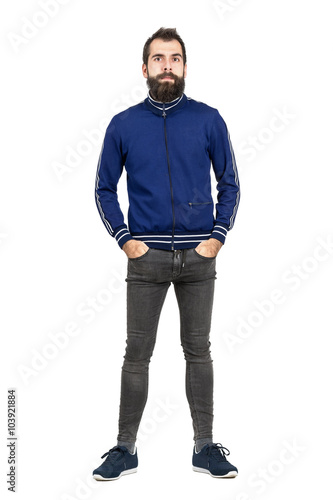 Serious bearded hipster with hands in pockets in old fashioned clothes looking at camera. Full body length portrait isolated over white studio background. 