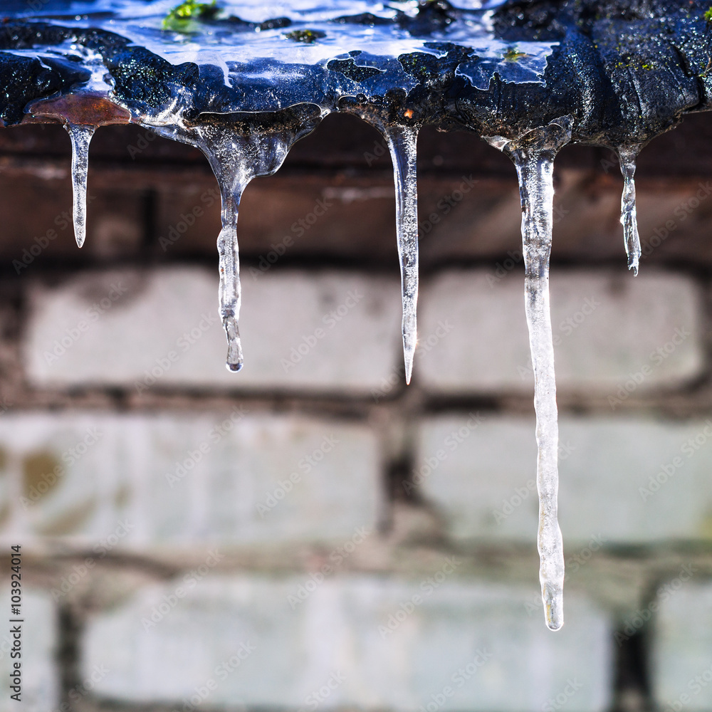 icicles on roof of barn with brick wall
