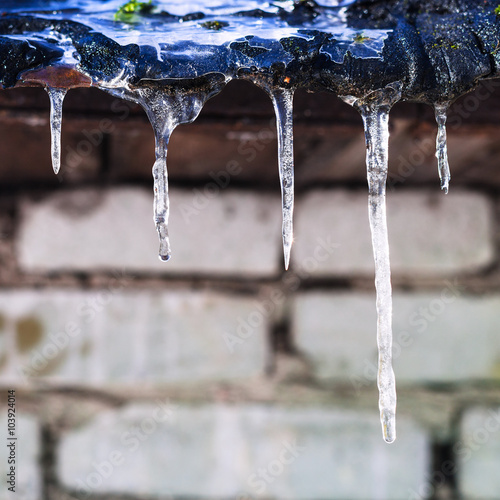 icicles on roof of barn with brick wall © vvoe