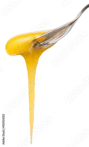 yellow honey flows down from teaspoon close up