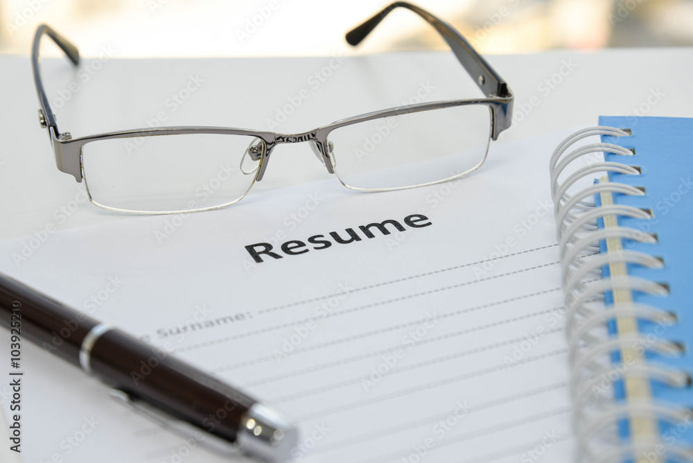 Draft of Resume with pen, notebook and eyeglasses Draft of Resume with pen, notebook and eyeglasses