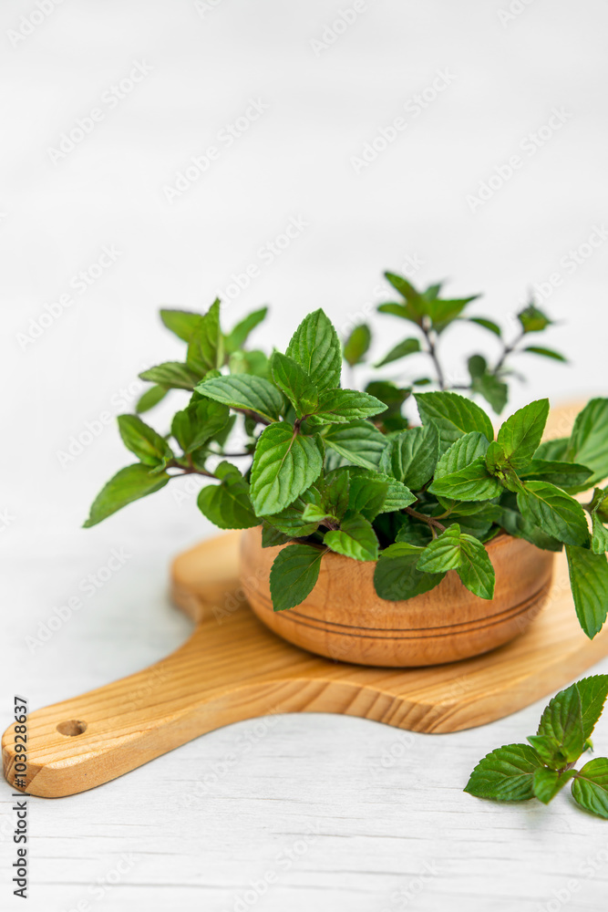Mint in small basket on natural wooden background, peppermint
