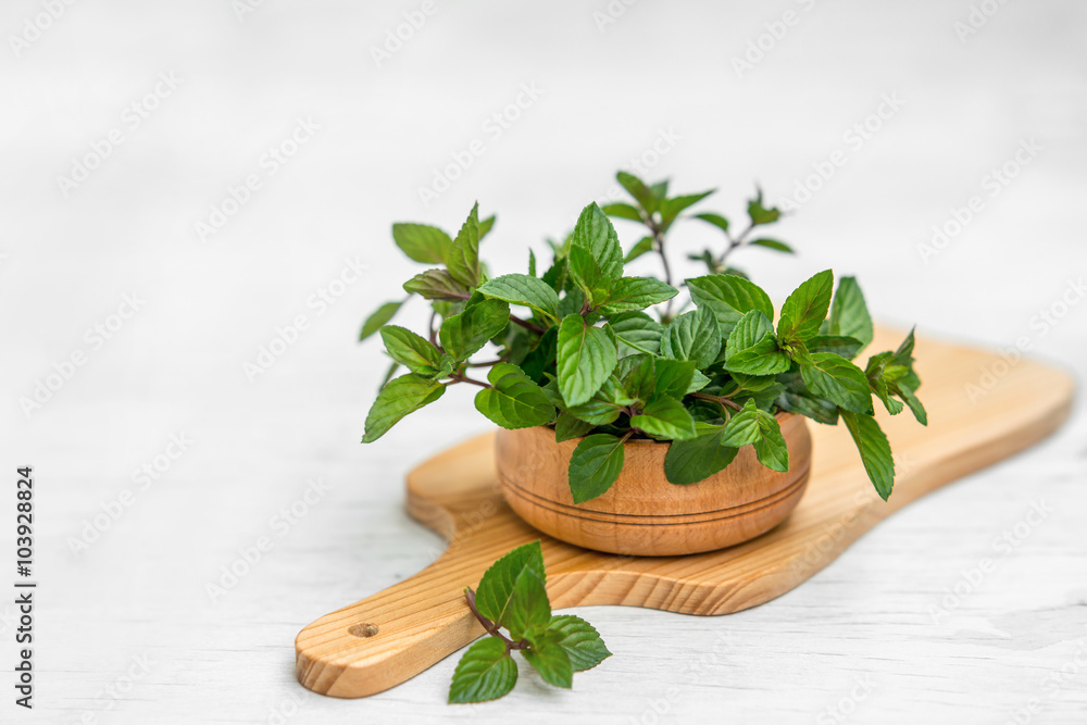 Mint in small basket on natural wooden background, peppermint