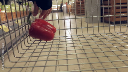 Shopping cart with vegetables and fruits moving through supermarket photo