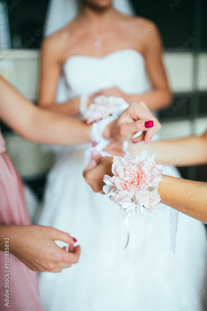 beautiful elegant bridesmaid putting on bracelet on the bride's hand on the background of a room in the morning beautiful elegant bridesmaid putting on bracelet on the bride's hand on the background of a room in the morning
