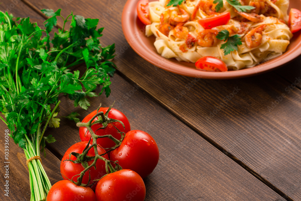 Fettuccine pasta with shrimp tomatoes and herbs. wooden background Fettuccine pasta with shrimp tomatoes and herbs. wooden background