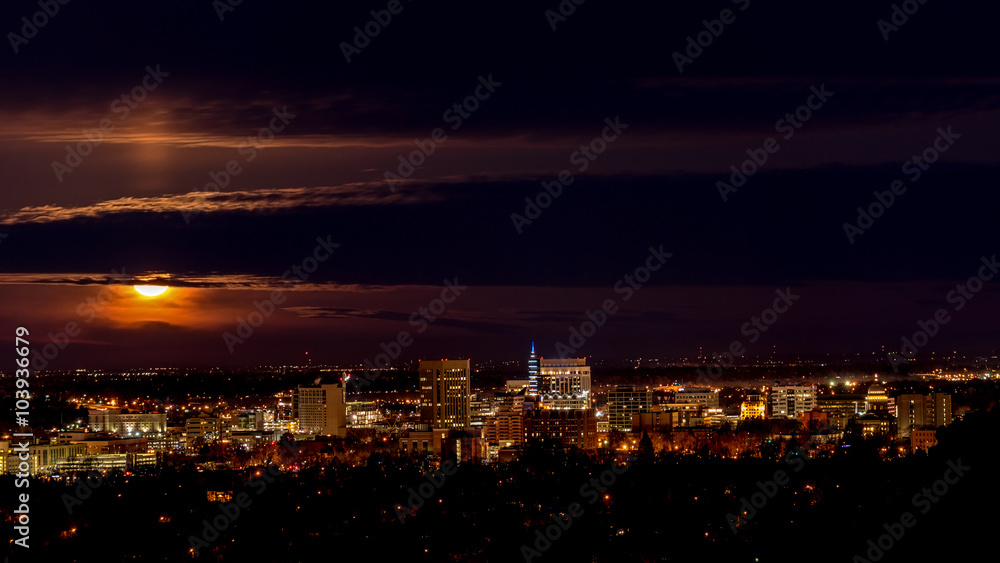 Skyling of Boise at night with full moon and clouds