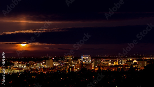 Skyling of Boise at night with full moon and clouds photo