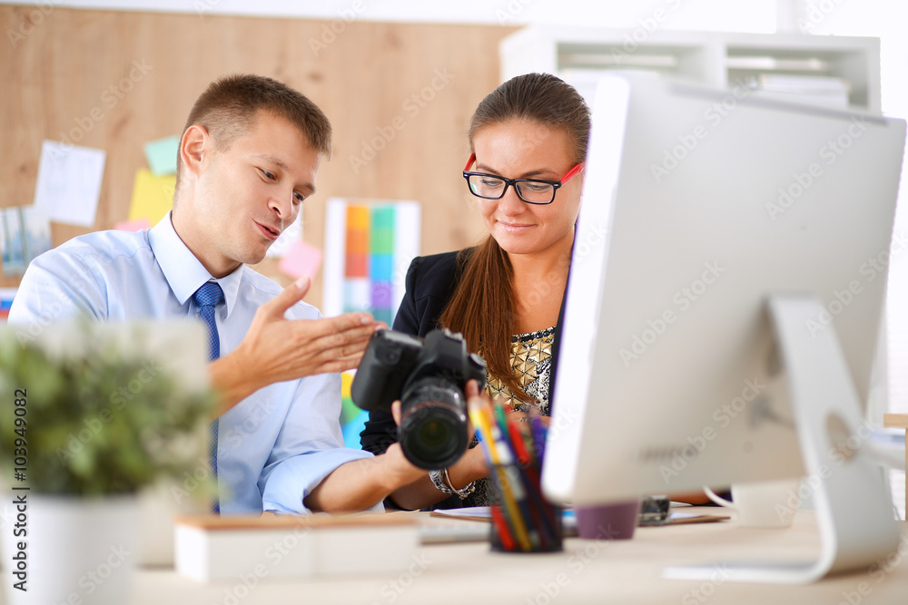 Fashion designers working in studio sitting on the desk Fashion designers working in studio sitting on the desk