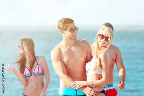 Happy couple and their playful friends relaxing at the beach, outdoors © Africa Studio