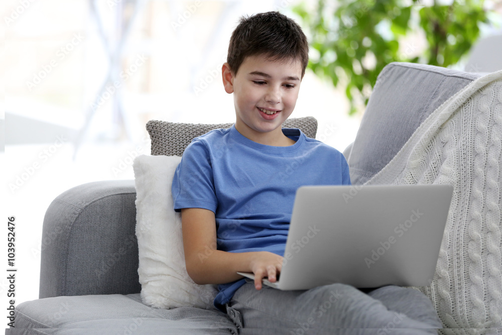 Little boy using laptop on a sofa at home Little boy using laptop on a sofa at home