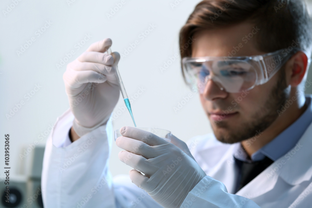 Serious clinician studying chemical element in laboratory Serious clinician studying chemical element in laboratory