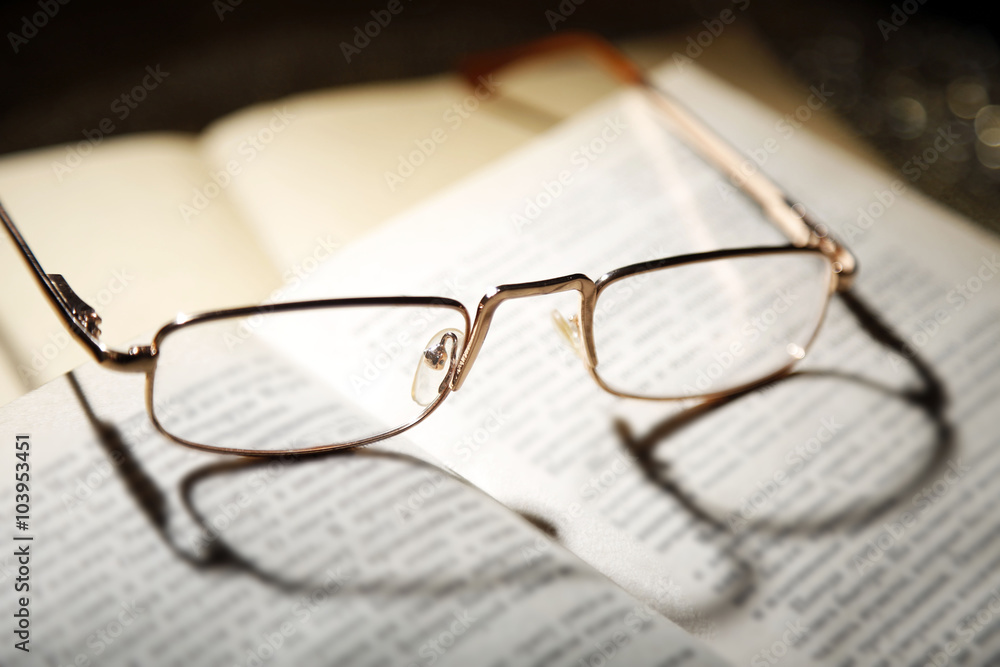 Opened book and eyeglasses on it, close up Opened book and eyeglasses on it, close up