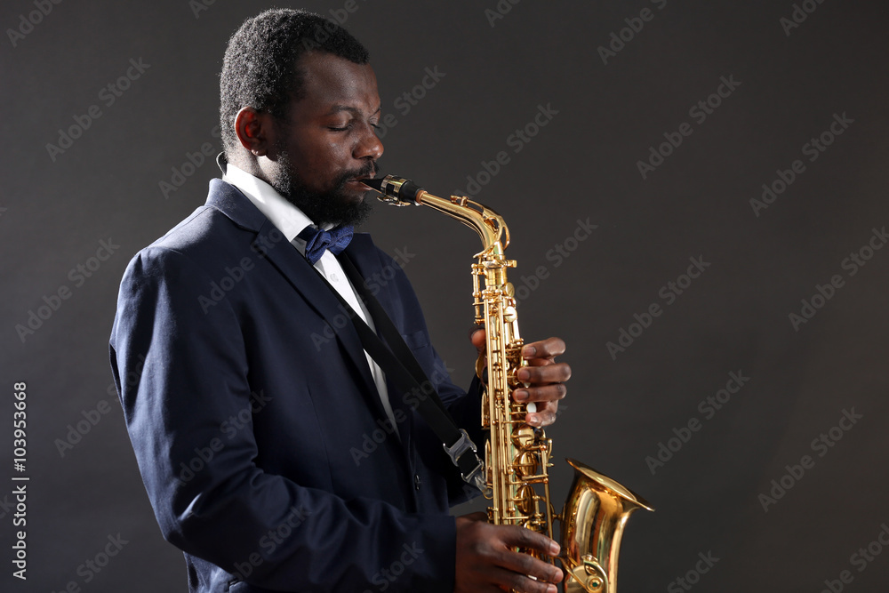 Fototapeta premium African American jazz musician playing the saxophone on grey background