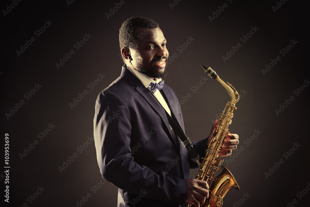 Fototapeta premium African American jazz musician playing the saxophone on grey background