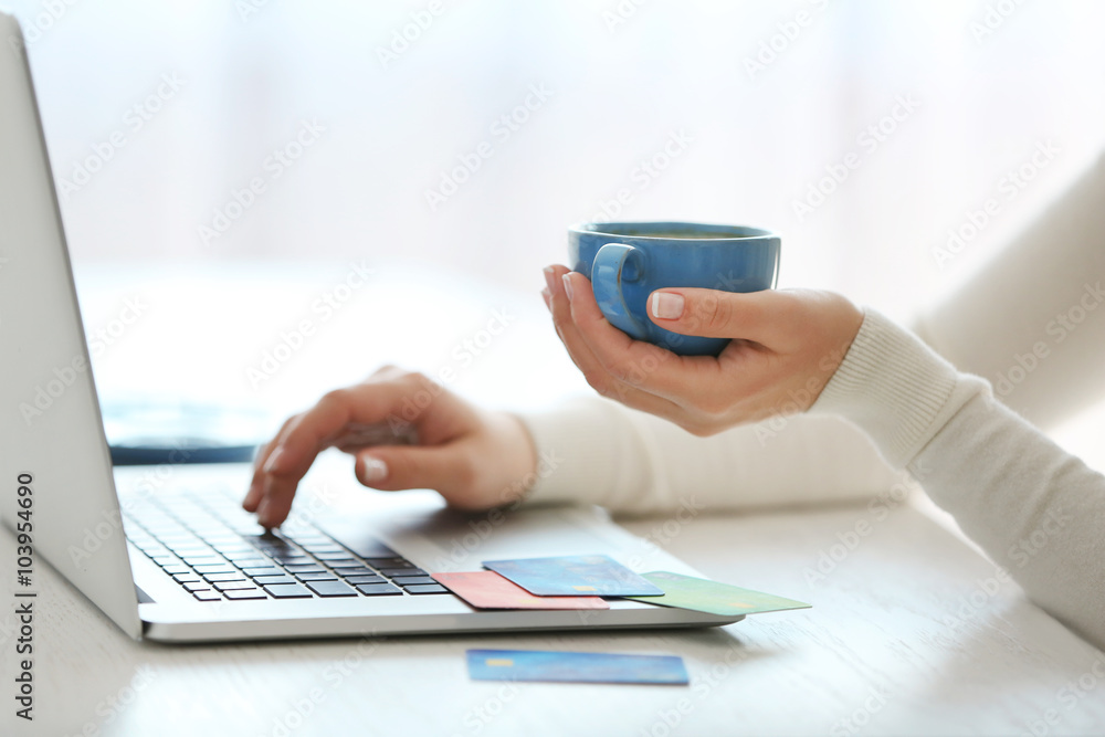 Fototapeta premium E-commerce concept. Woman with credit card, laptop and cup of coffee, close up
