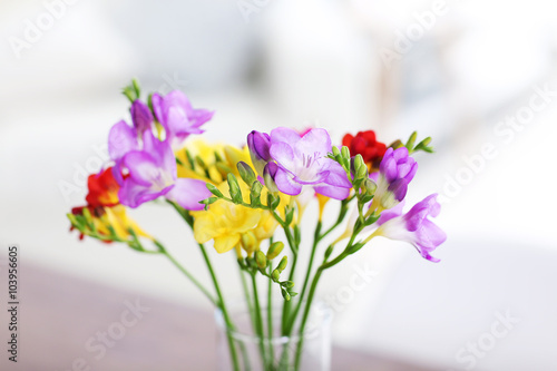 Beautiful bouquet of colorful freesias flowers on wooden table at living room