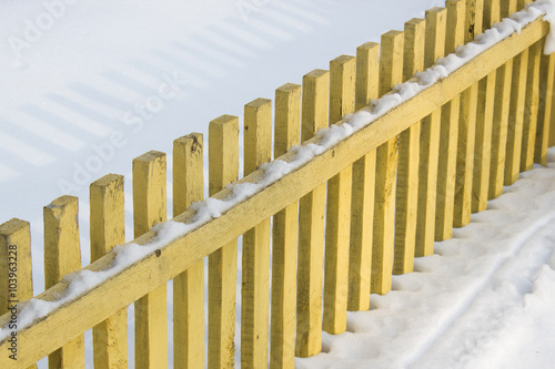 Yellow wooden fence in the snow