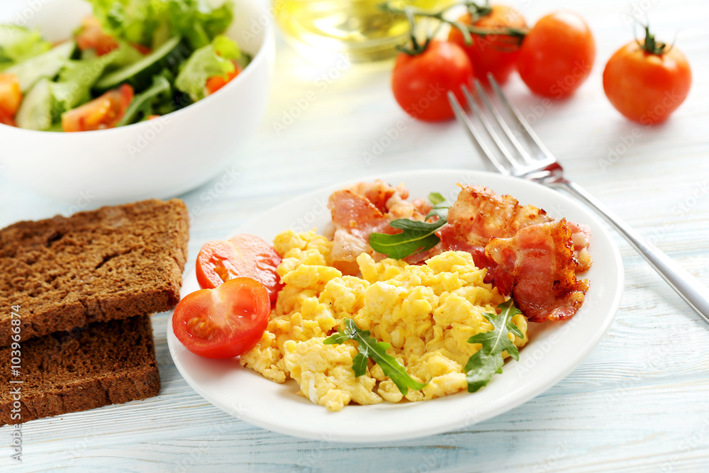 Scrambled eggs with bacon and vegetables on a blue wooden table Scrambled eggs with bacon and vegetables on a blue wooden table