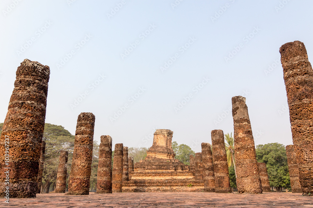 An ancient temple ruin with slanted laterite/sandstone pagoda in the area of Sukhothai's UNESCO world heritage park, Thailand. The place is public property, no release document required.