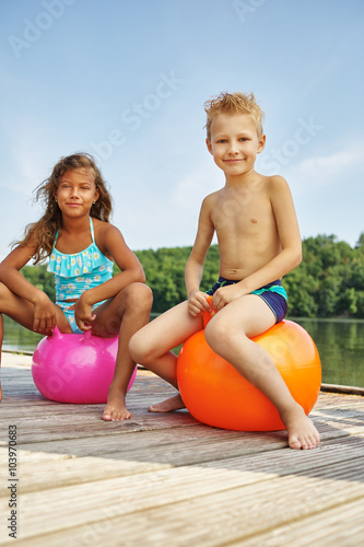 Kinder spielen mit Hüpfbällen am See