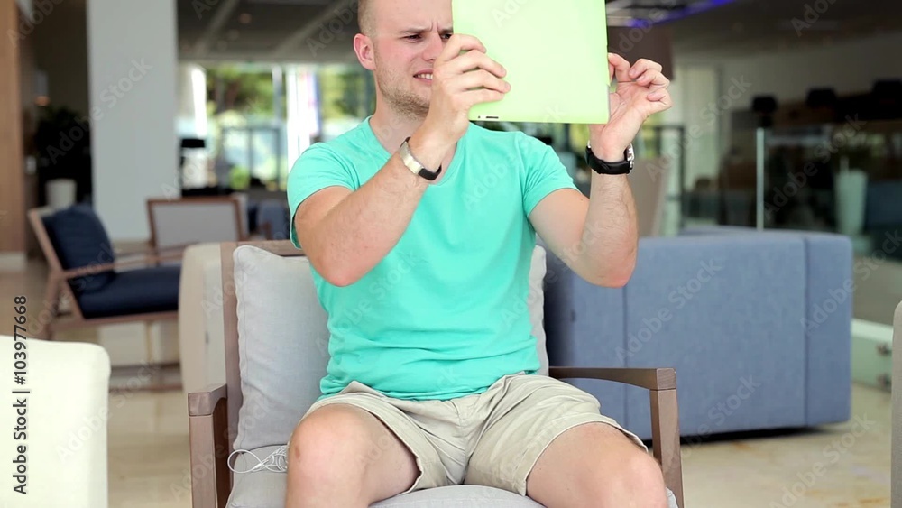 Young man taking pictures on tablet pc in hotel lobby. Young man taking pictures on tablet pc in hotel lobby.