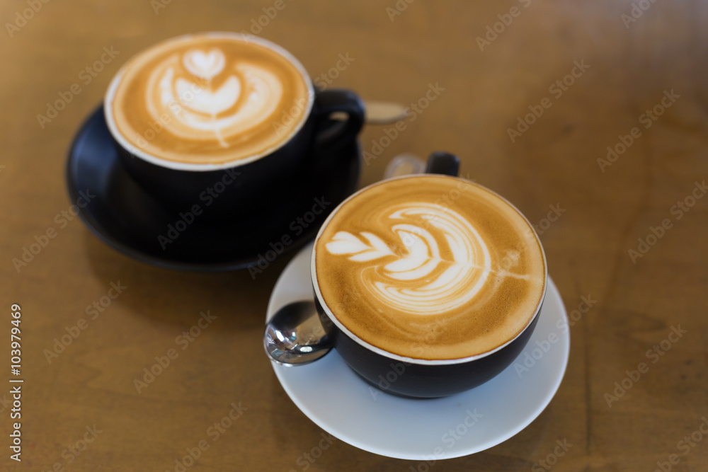 two cup of hot latte art coffee in black mug two cup of hot latte art coffee in black mug
