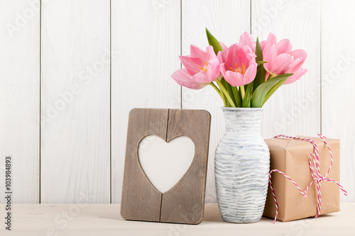 Fresh pink tulips, blank frame and gift box