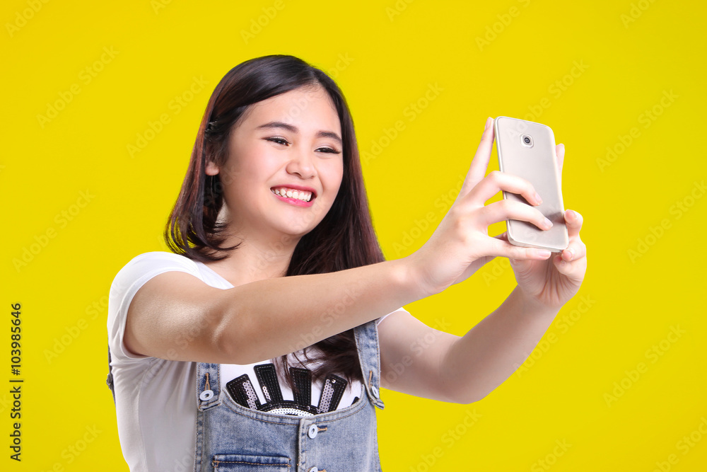 Cute smiling girl taking selfie, over yellow Cute smiling girl taking selfie, over yellow
