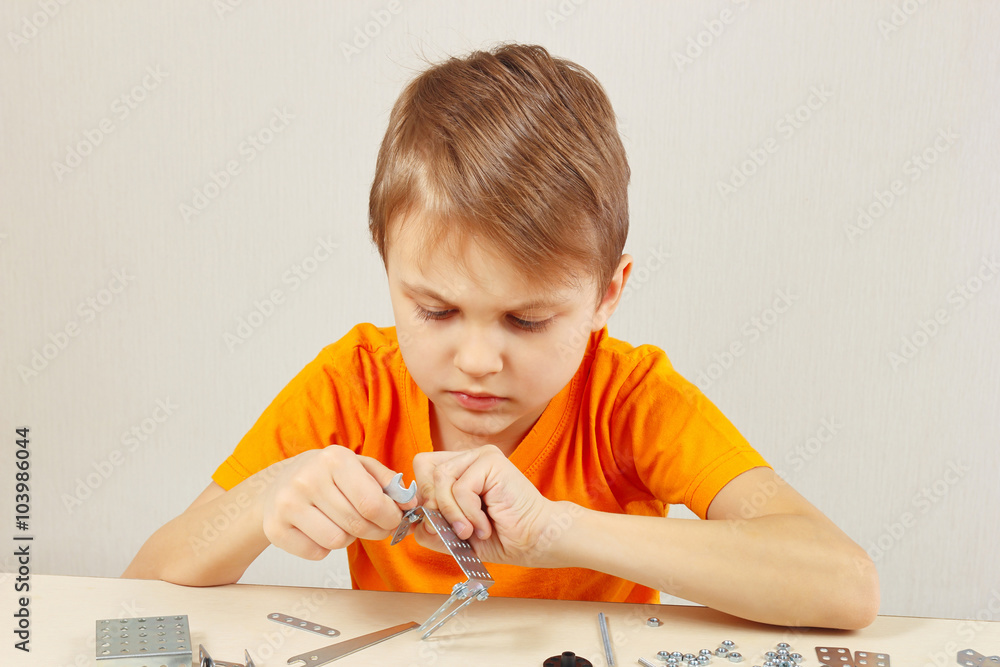 Little cute boy plays with mechanical kit at the table Little cute boy plays with mechanical kit at the table