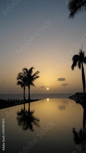 a setting sun reflects of a caribbean pool 