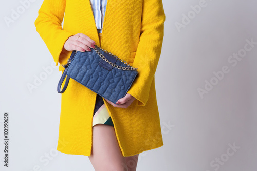 Beautiful woman in yellow spring or autumn coat with blue bag