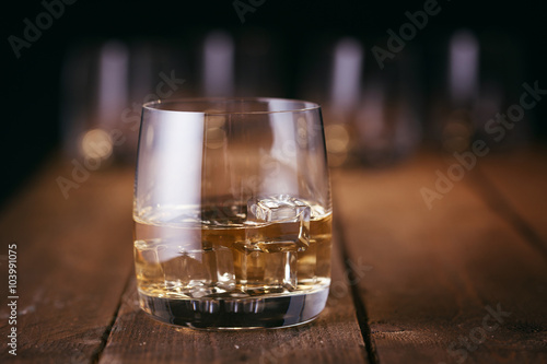 Photos Glass of whiskey with ice cubes on wood table