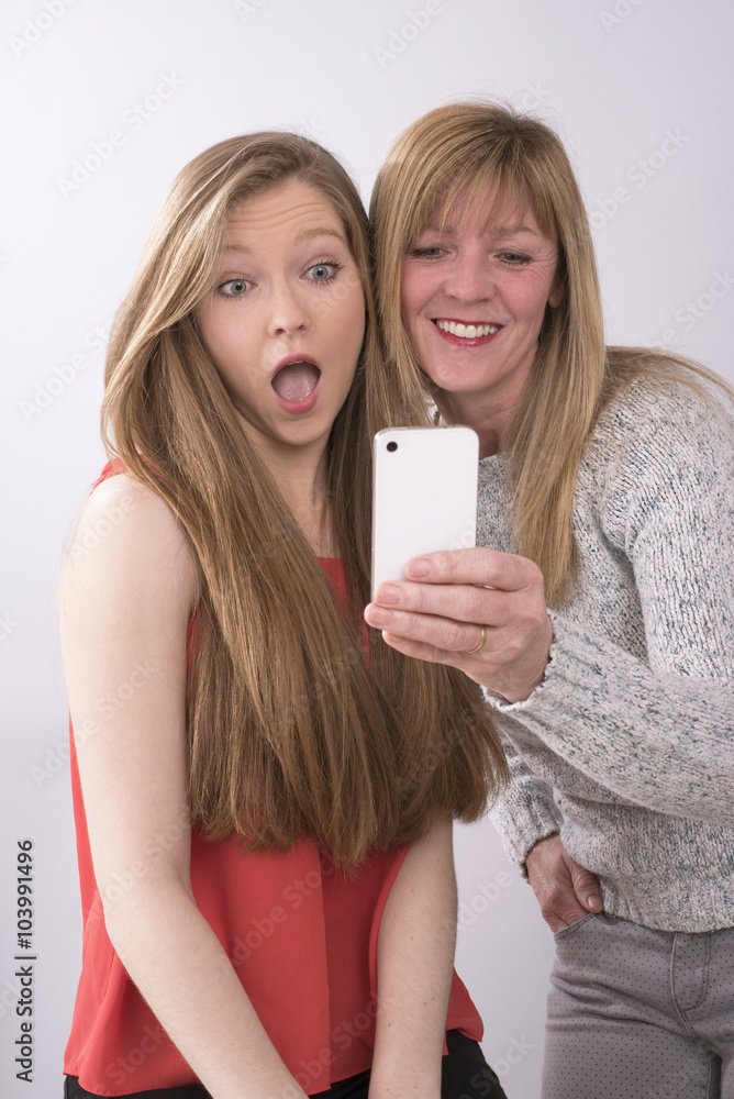 Expressive portrait of mother and daughter using a mobile phone Expressive portrait of mother and daughter using a mobile phone