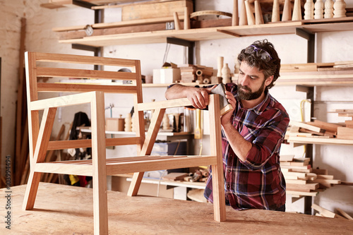 Fotografie Furniture designer sanding a wooden chair frame