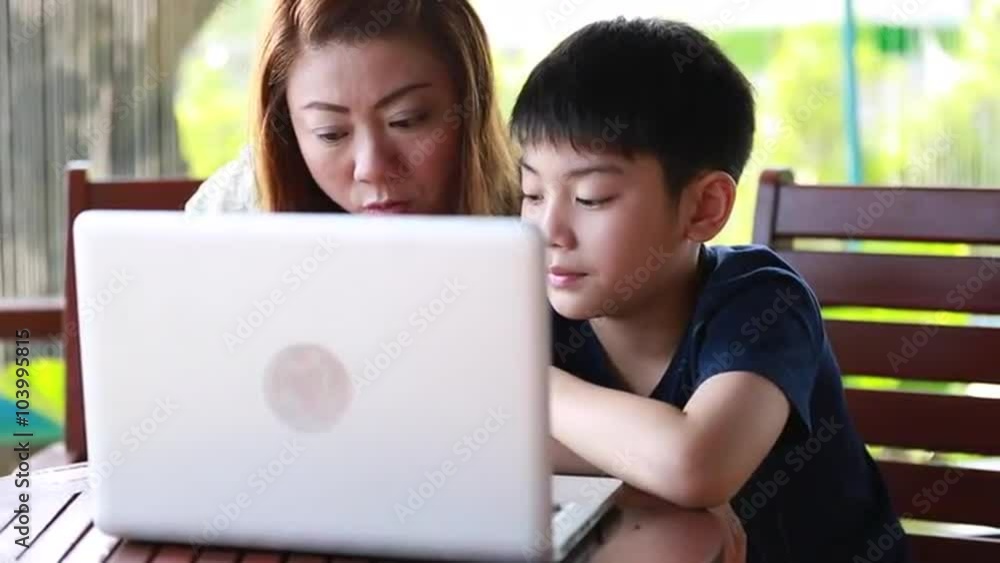 Young, happy asian mother with child using laptop on terrace Young, happy asian mother with child using laptop on terrace