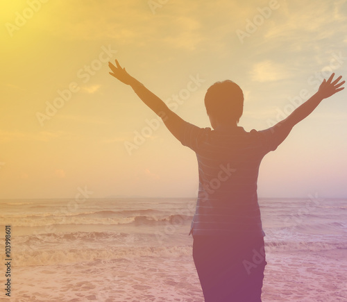 Woman open arms under sunset at the beach in vintage tone.