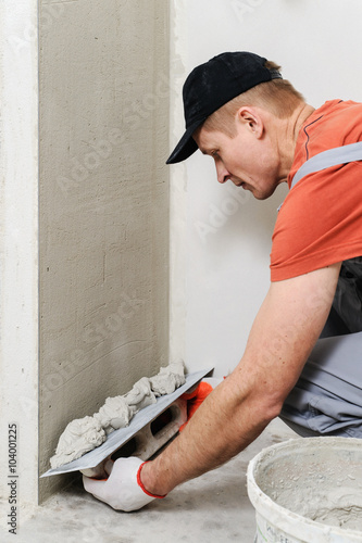 The worker puts the stucco on the wall photo