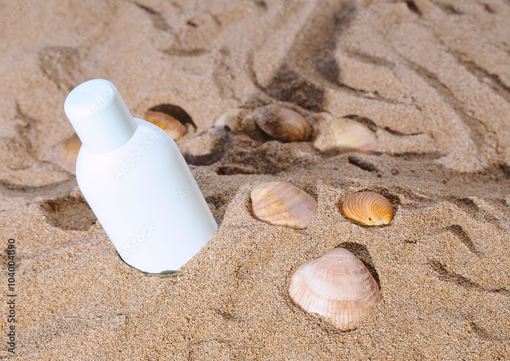 Sun lotion and several sea shells on sand Sun lotion and several sea shells on sand